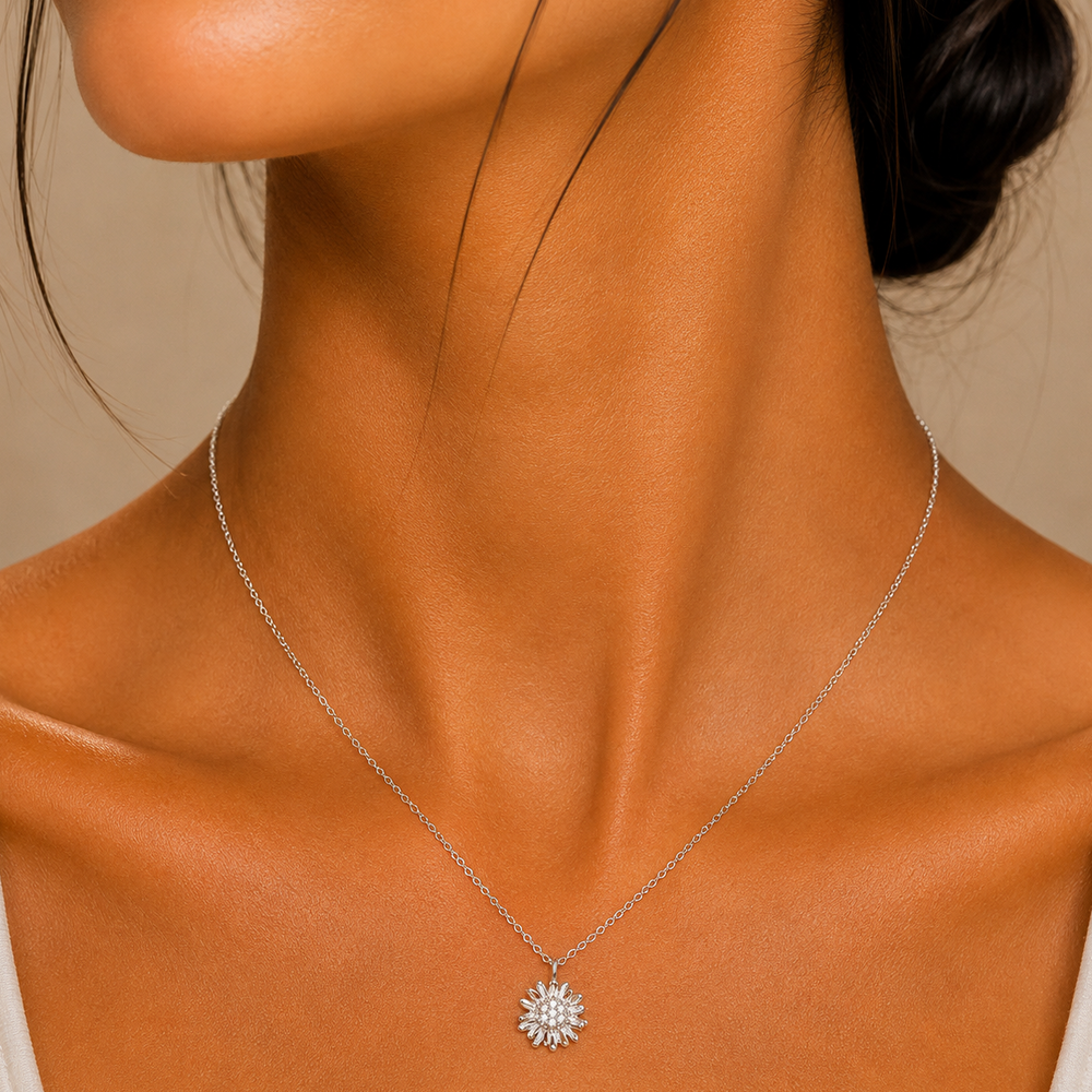 Close-up of a woman wearing a silver necklace with a sunflower pendant against a neutral background