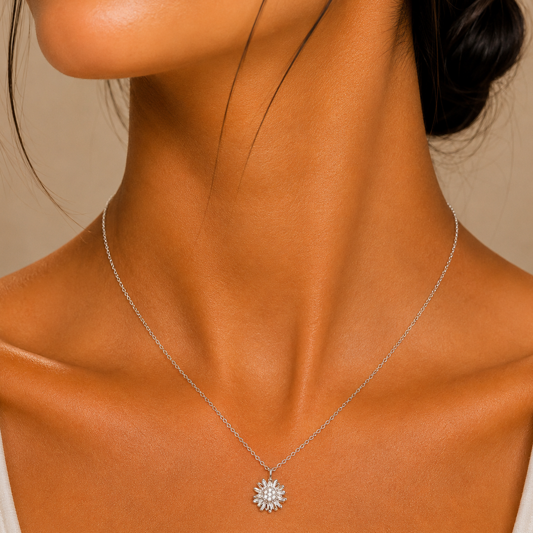 Close-up of a woman wearing a silver necklace with a sunflower pendant against a neutral background
